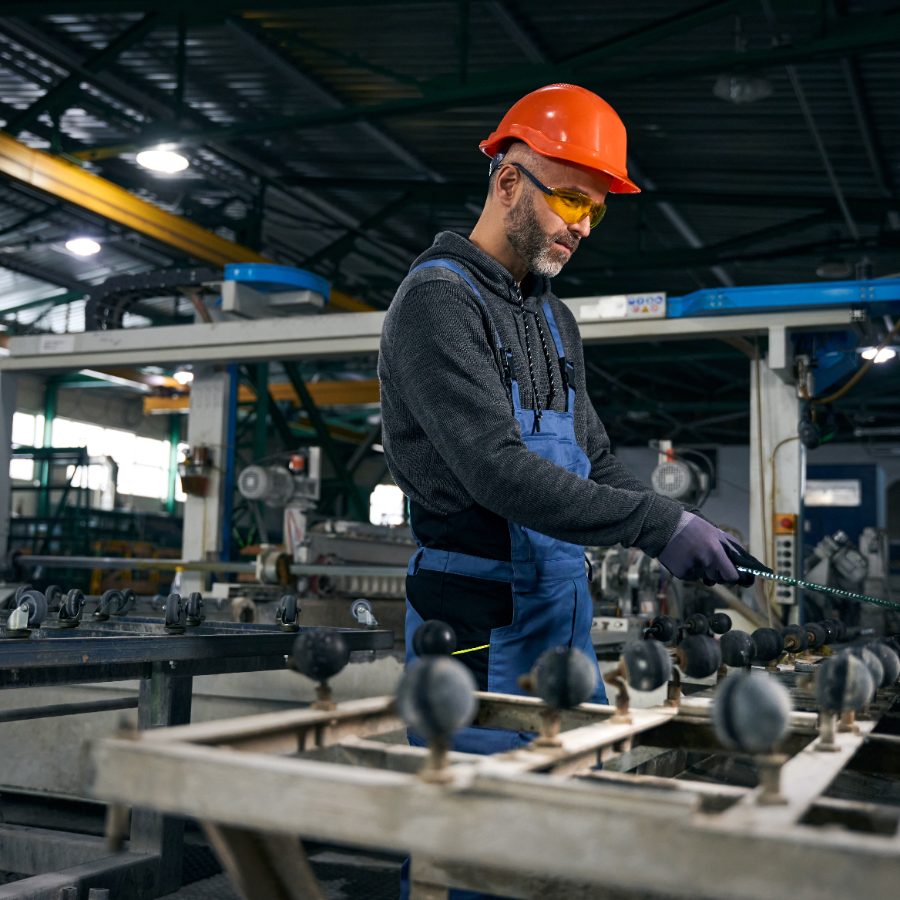 A technician measuring parts on a factory line